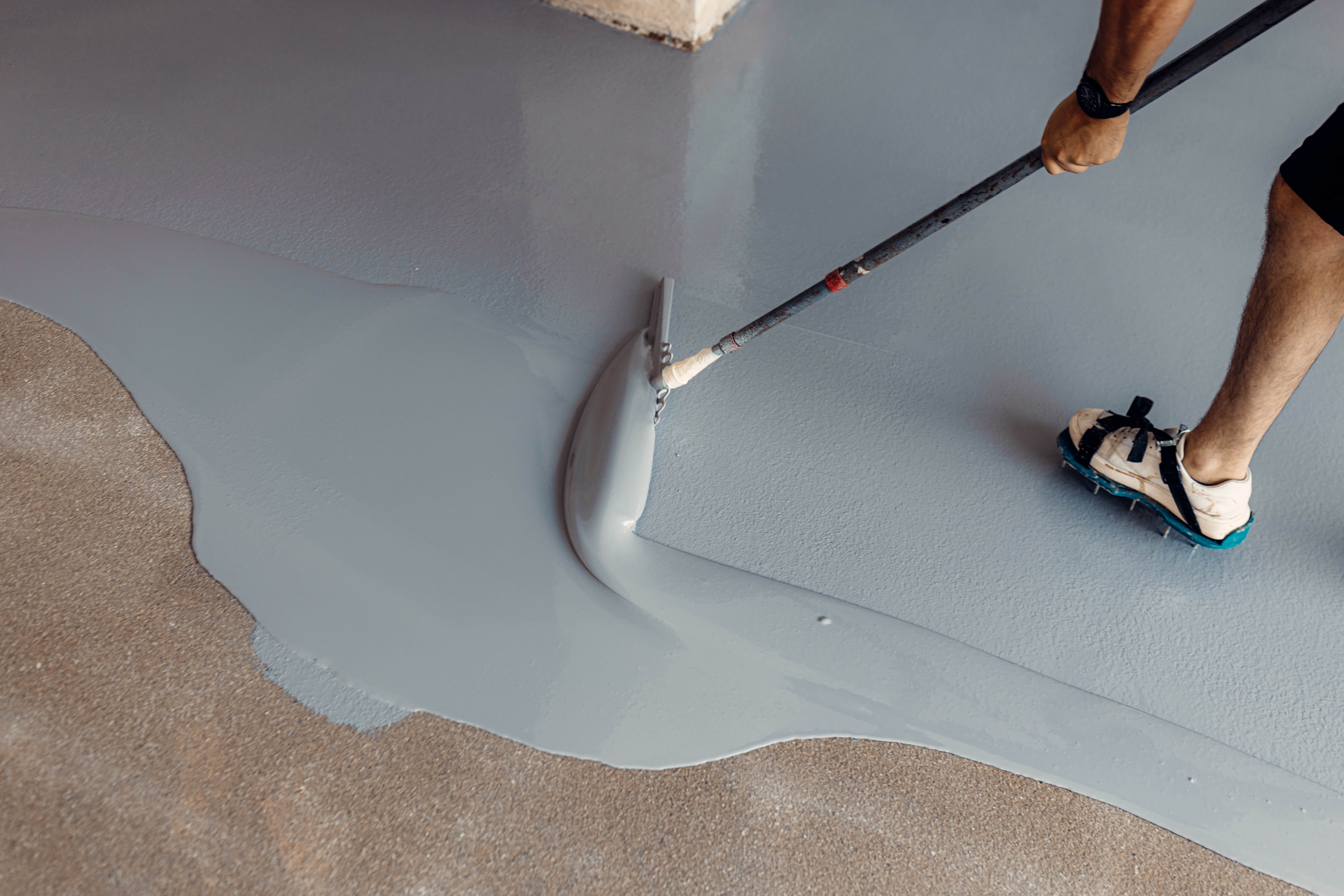Self-levelling decorative layer being squeegeed across a residential floor